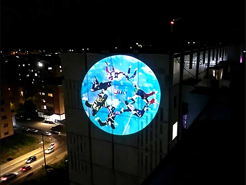 A large outdoor image projected onto a building facade at night